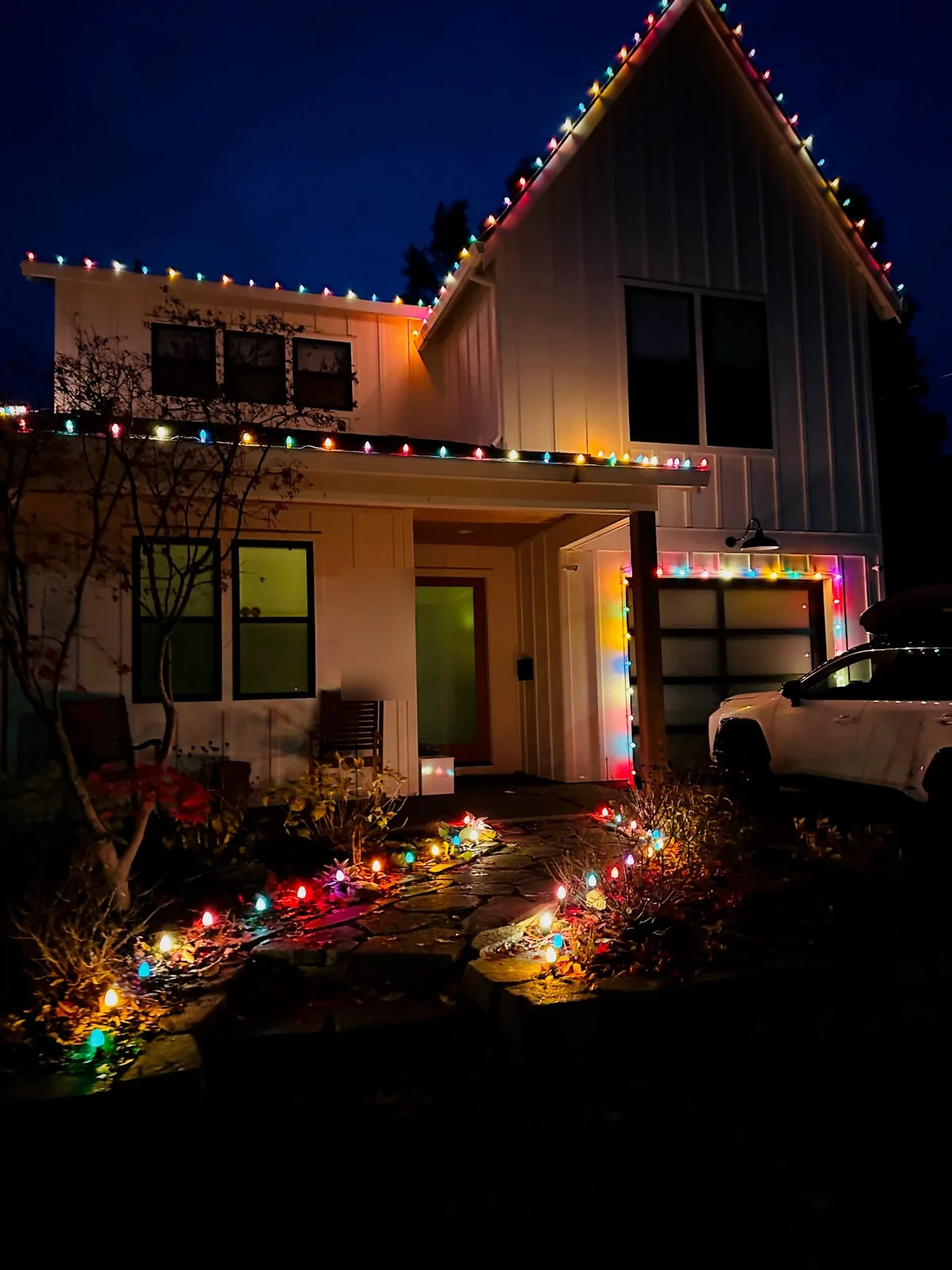 Modern farmhouse with multicolor C9 roofline lights and matching pathway lighting through the front garden